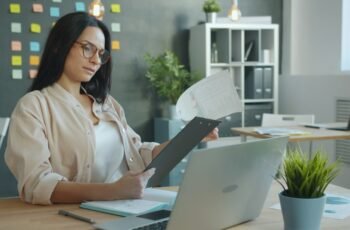 Professional reviewing documents and a laptop at work